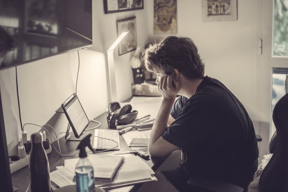 Person am Schreibtisch im Homeoffice, mit Tablet, Tastatur und Notizen